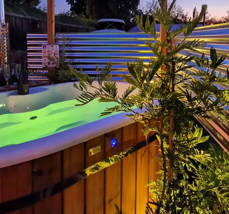 Hot tub lit with green LED lighting in a garden at dusk