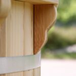 Close-up of carved wooden post with metal banding, outdoor blurred background.