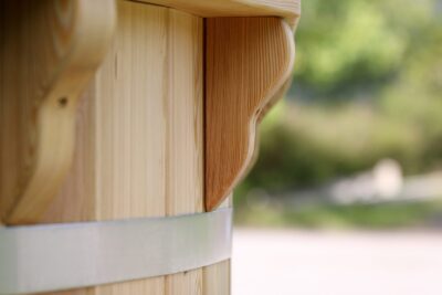 Close-up of carved wooden post with metal banding, outdoor blurred background.