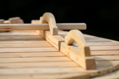 Close-up of wooden toy train tracks with curved pieces on a light wooden surface.