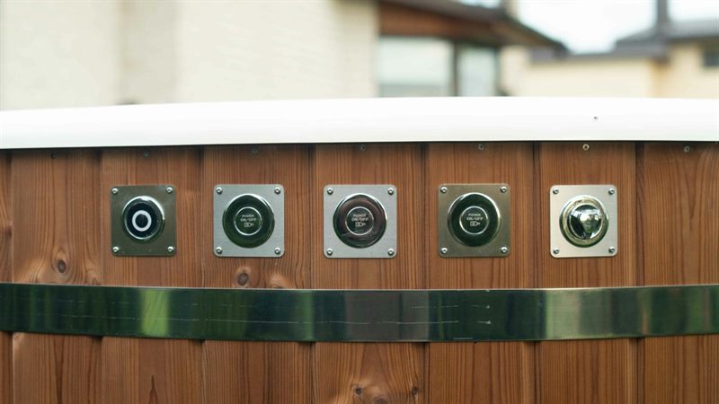Row of five metal power sockets and switches mounted on a wooden panel with chrome trim.